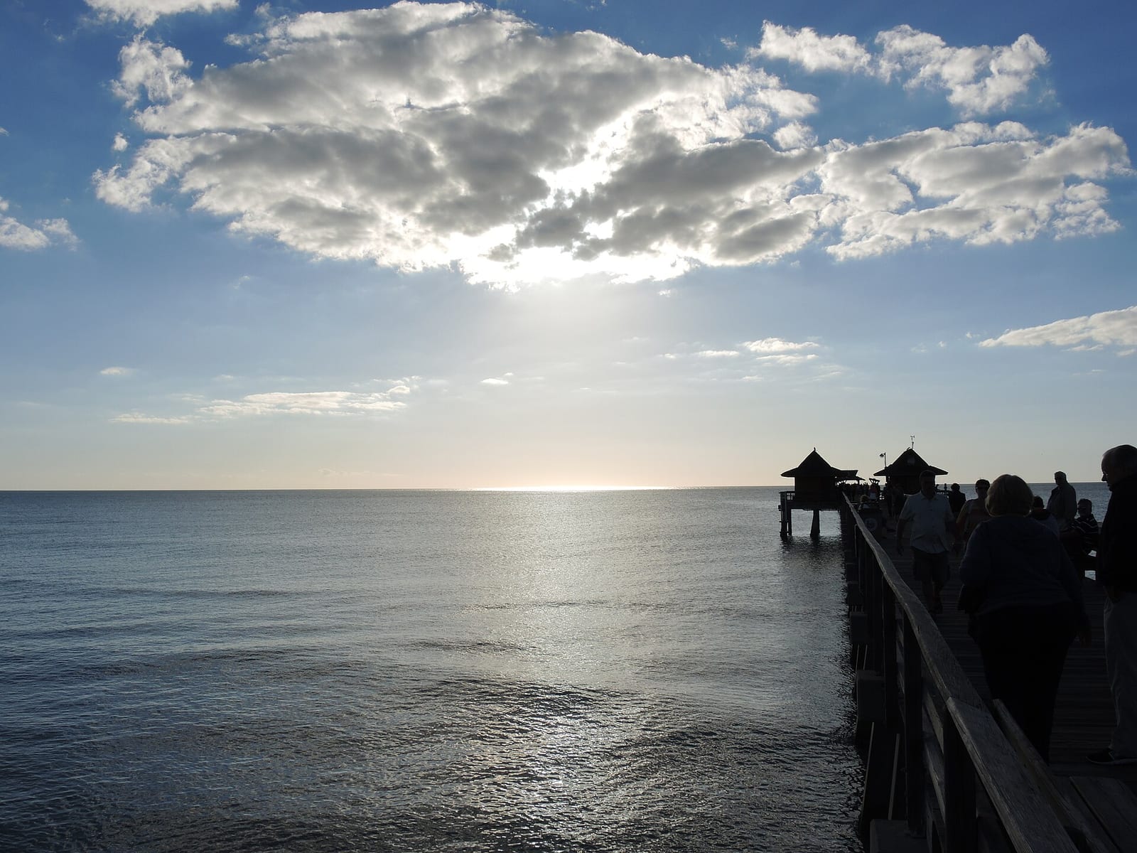 13th Avenue South Beach: pier extending into ocean with silhouetted visitors, cloudy sky