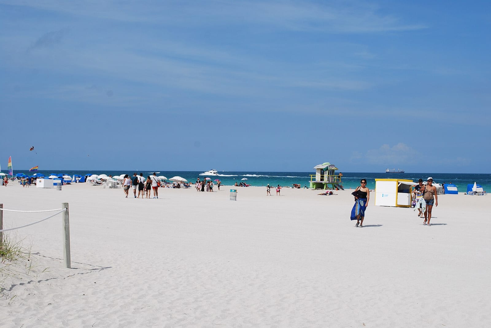 Miami Beach: wide sandy beach with swimmers, lifeguard tower, umbrellas, clear sky