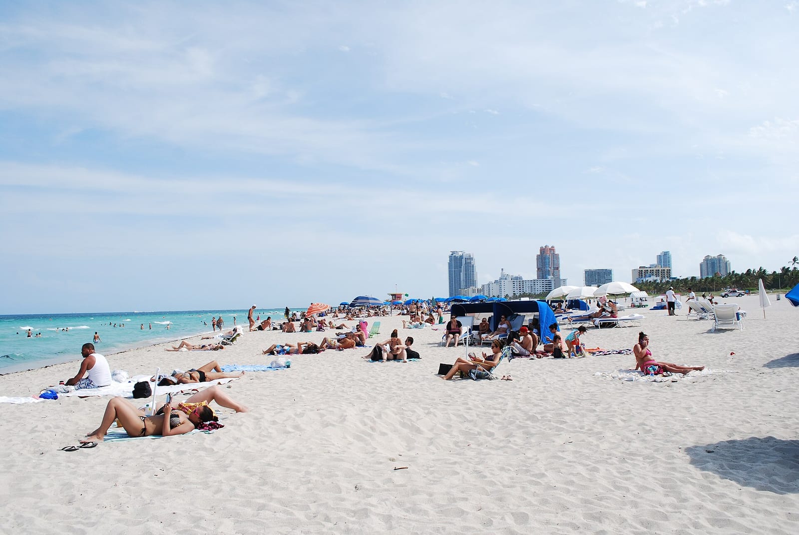 Miami Beach: crowded sandy beach with swimmers, sunbathers, and cityscape skyline background