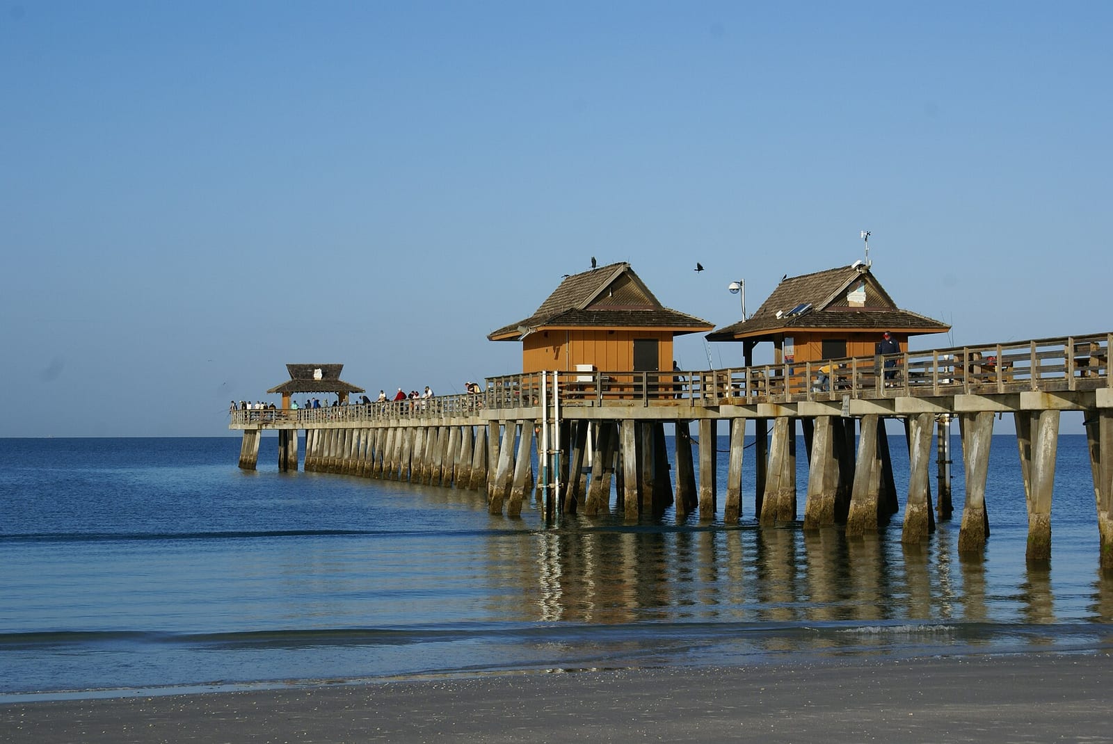 4th Avenue North Beach: wooden pier with pavilion structures extending into calm ocean water