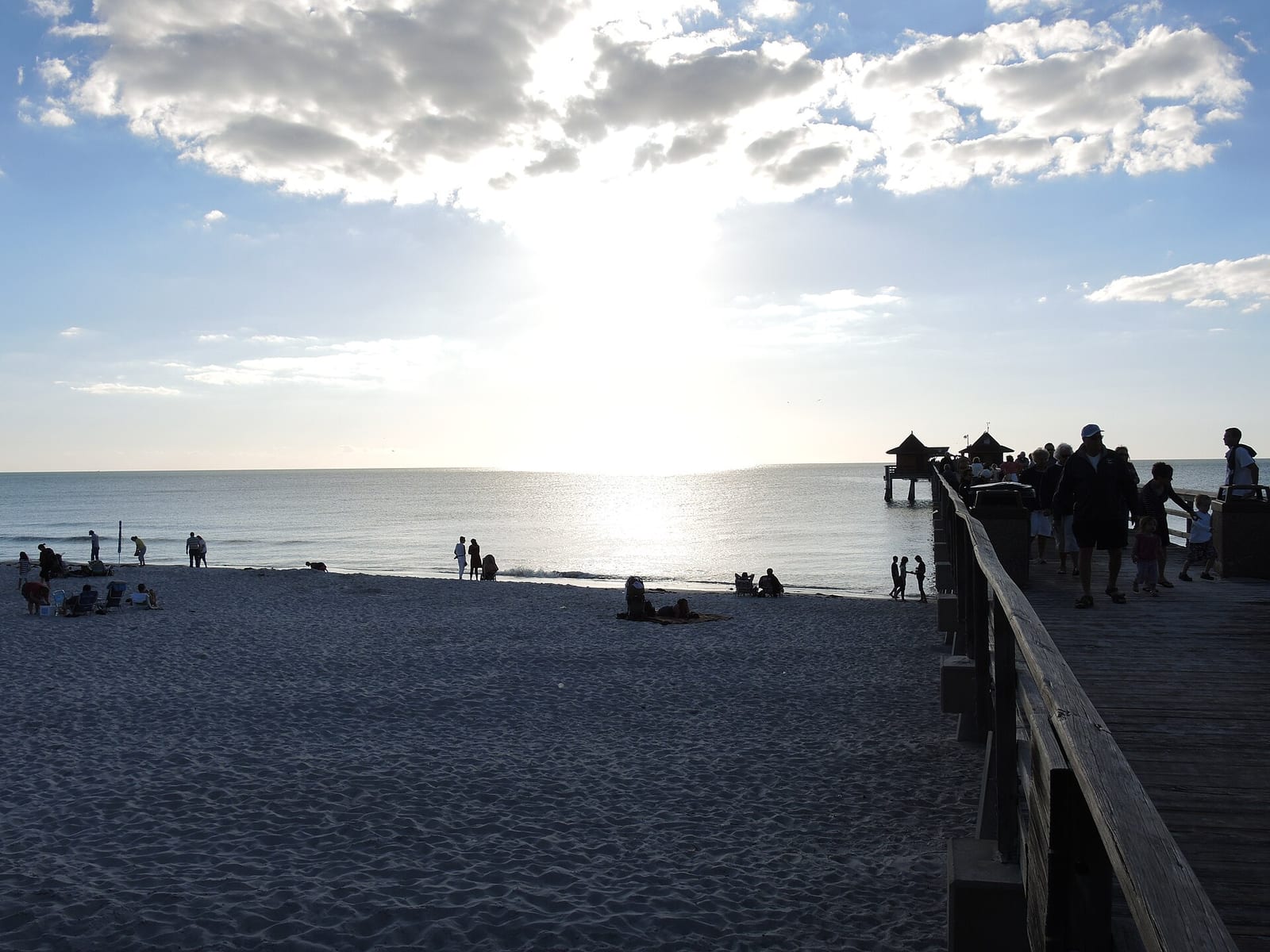 7th Avenue South Beach: sandy beach with pier, ocean, scattered visitors, cloudy sky
