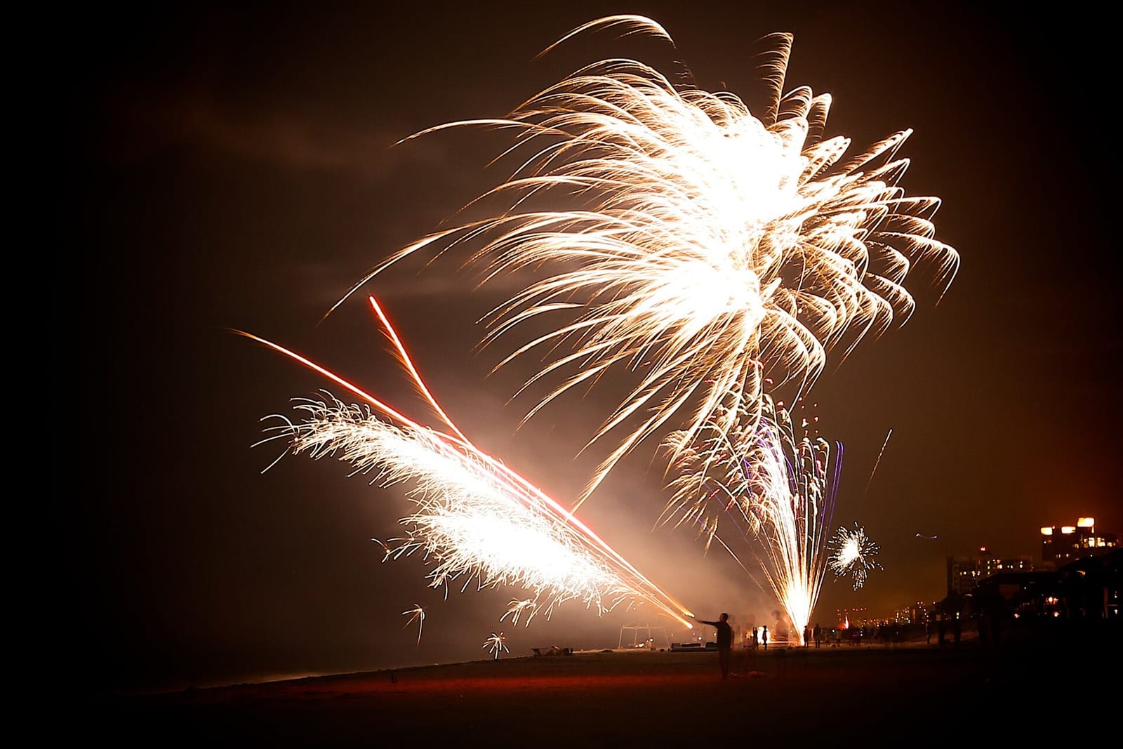 Belleair Beach: fireworks display over beach at night with buildings silhouetted