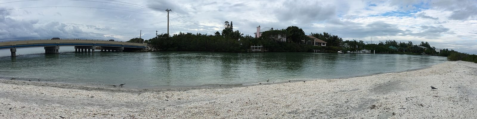 Blind Pass Beach: sandy beach with calm shallow water and distant island with buildings
