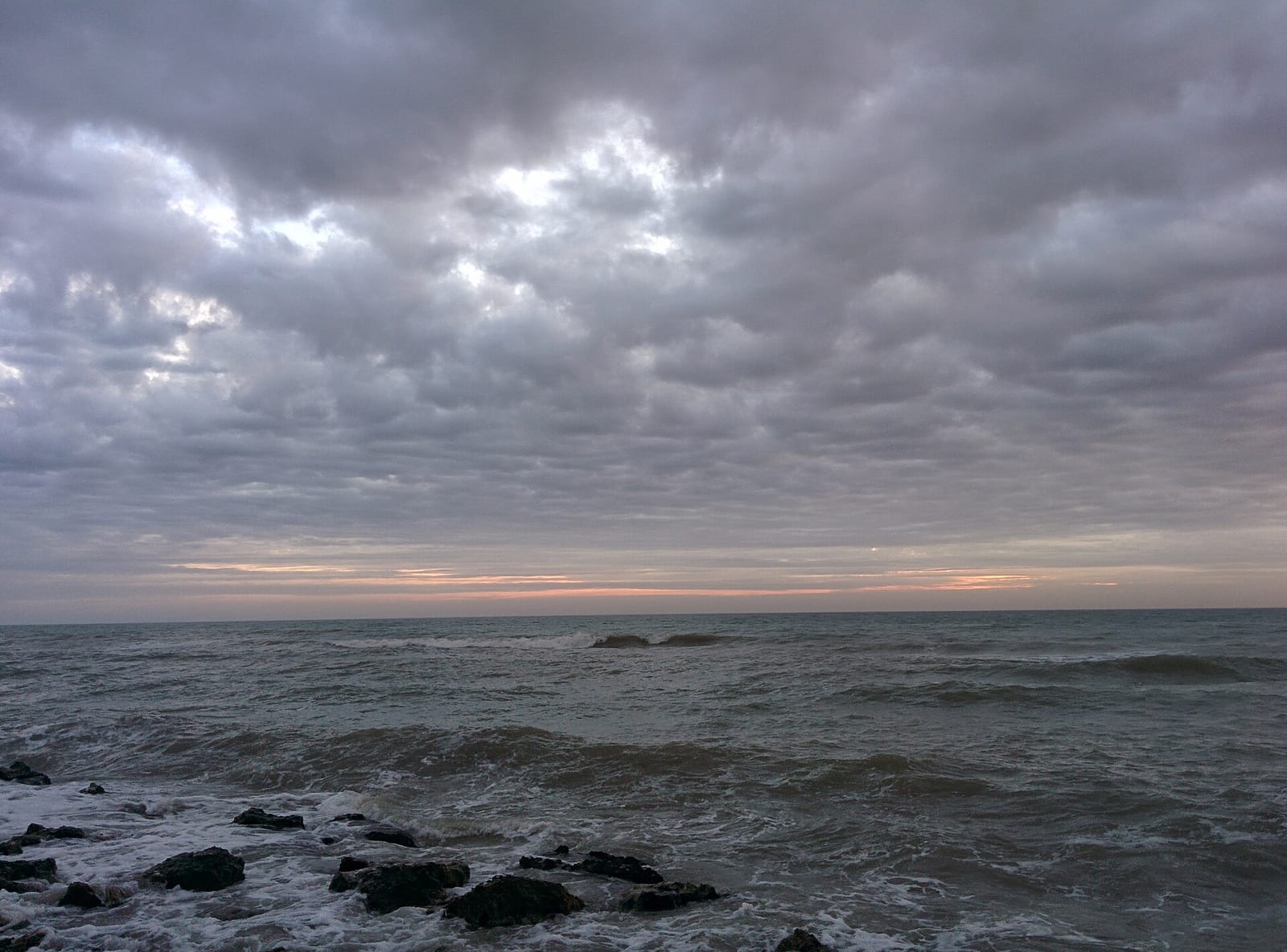 Caspersen Beach: rocky shoreline with waves and dramatic cloudy sky at dusk