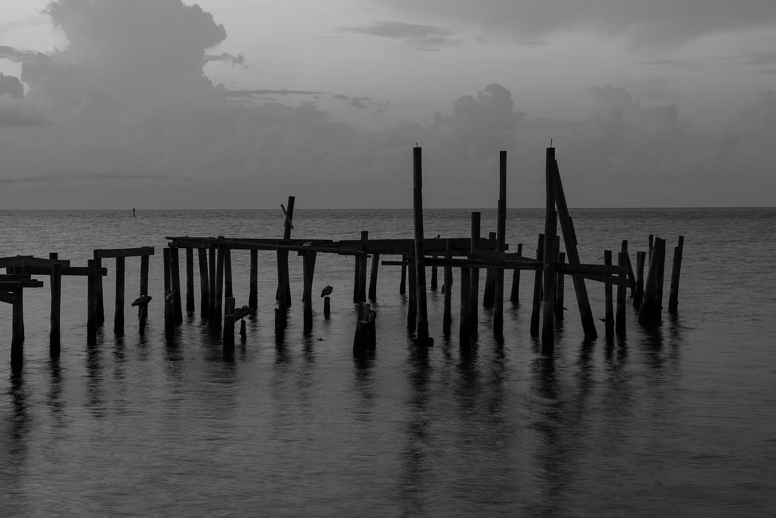 City Beach: abandoned wooden pier structure in shallow water, overcast sky