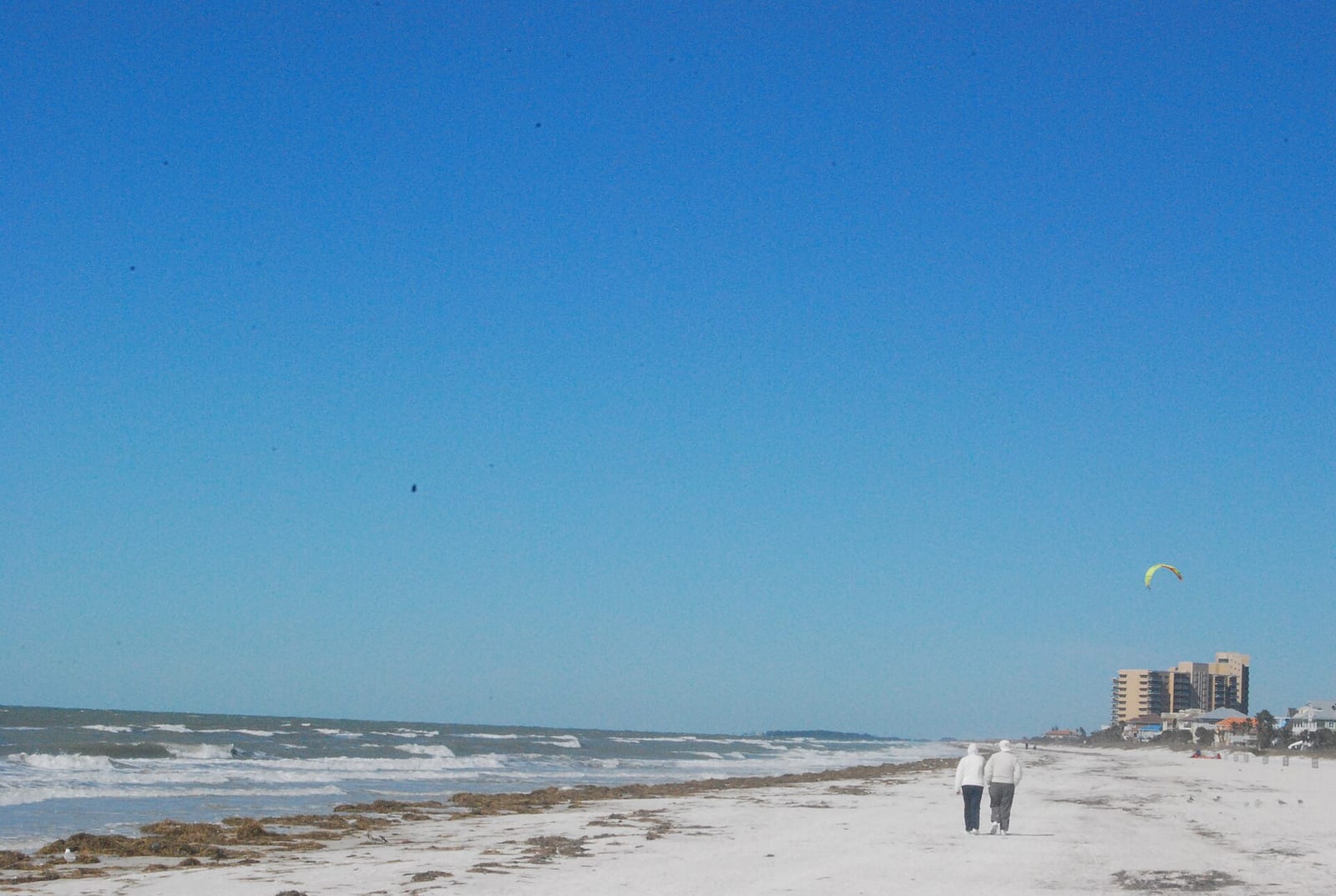 Clearwater Beach: beach shoreline with waves, two distant figures, beachfront buildings, clear sky