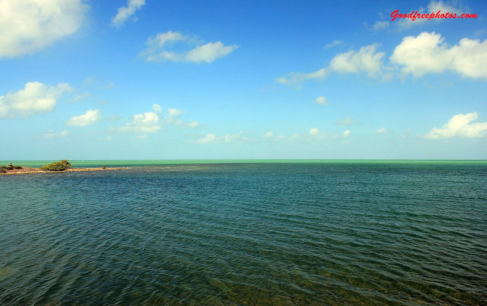 Coca Plum Beach: shallow turquoise water with distant mangrove island and blue sky