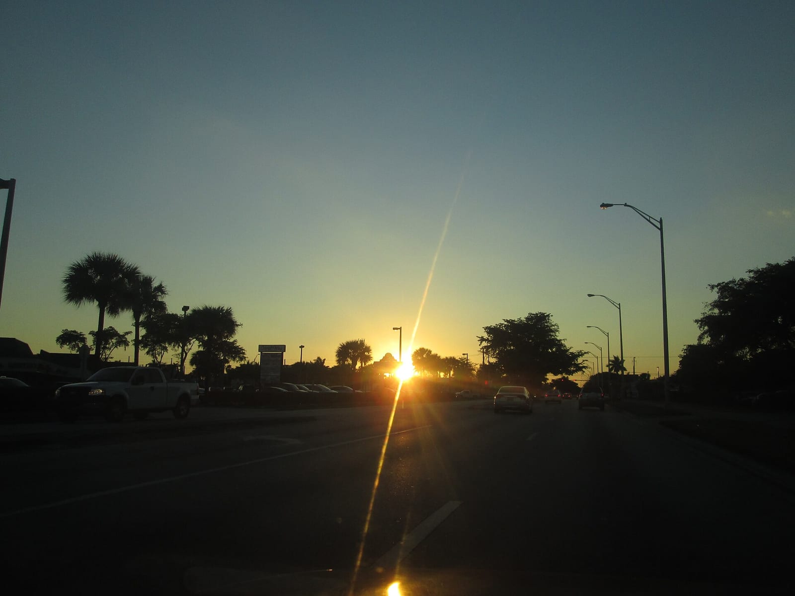 Crandon Park Beach: sunset over parking lot with palm trees and street lights