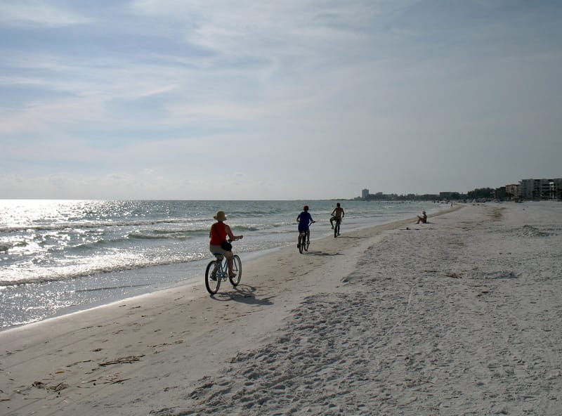 Crescent Beach: people cycling and walking on sandy beach near ocean shore
