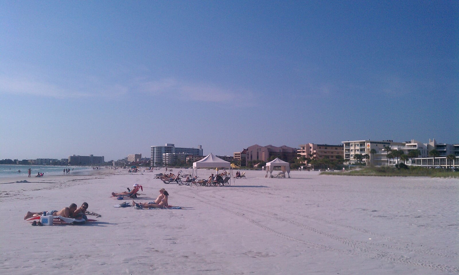 Cresent Beach: sandy beach with swimmers, beachgoers, tents, and waterfront buildings