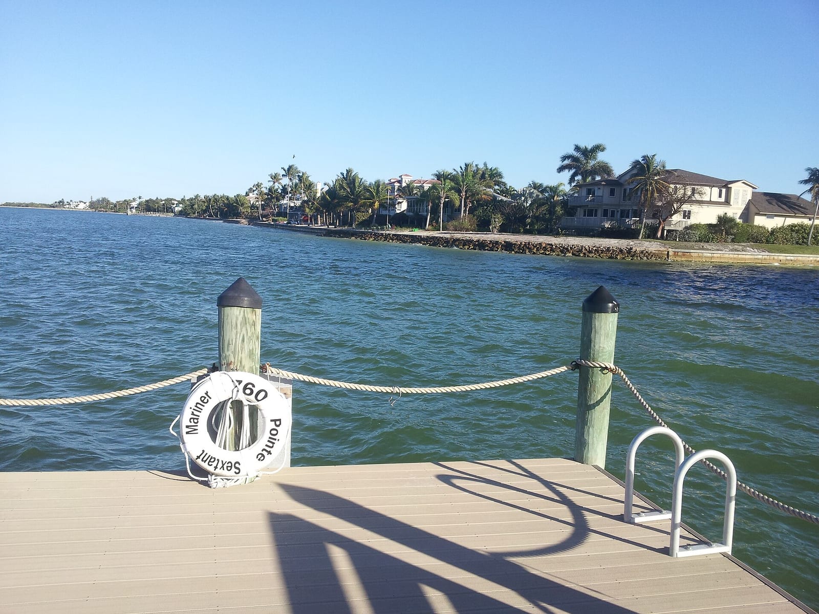 Dixie Beach: pier with mooring posts overlooking waterfront homes and palm trees