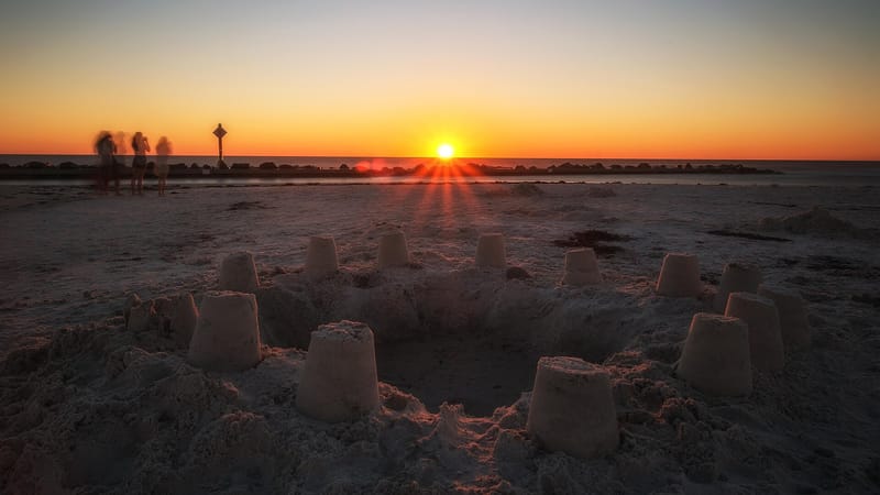 Dunedin Beach: sand castles on beach at sunset with distant figures and cross