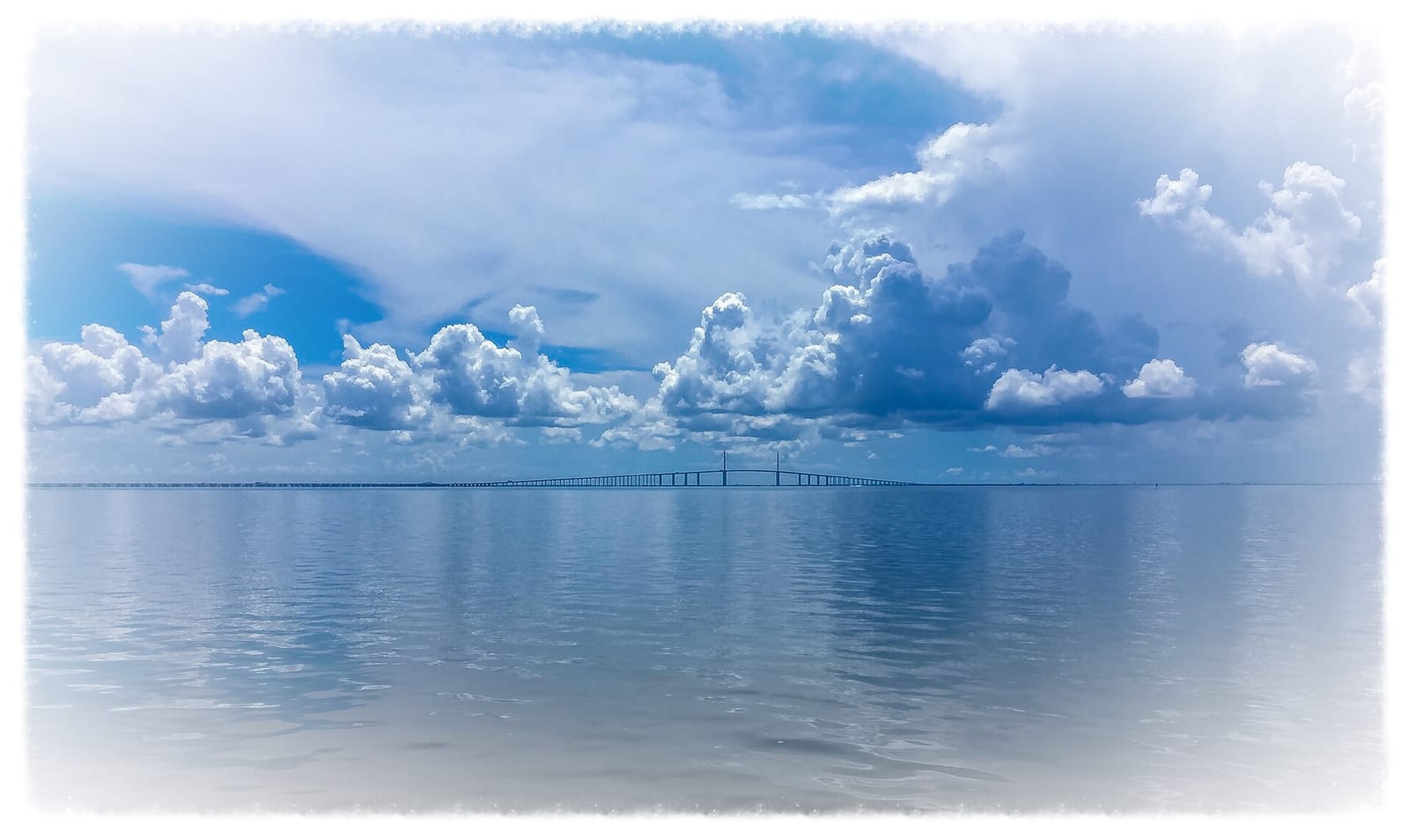 East Beach: bridge spanning calm water under dramatic cloudy sky