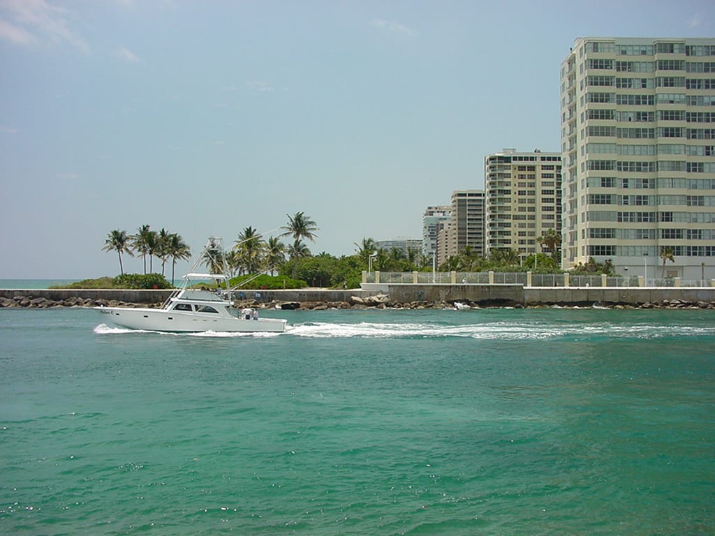 Haulover Beach: motorboat in turquoise water with high-rise buildings and palm trees
