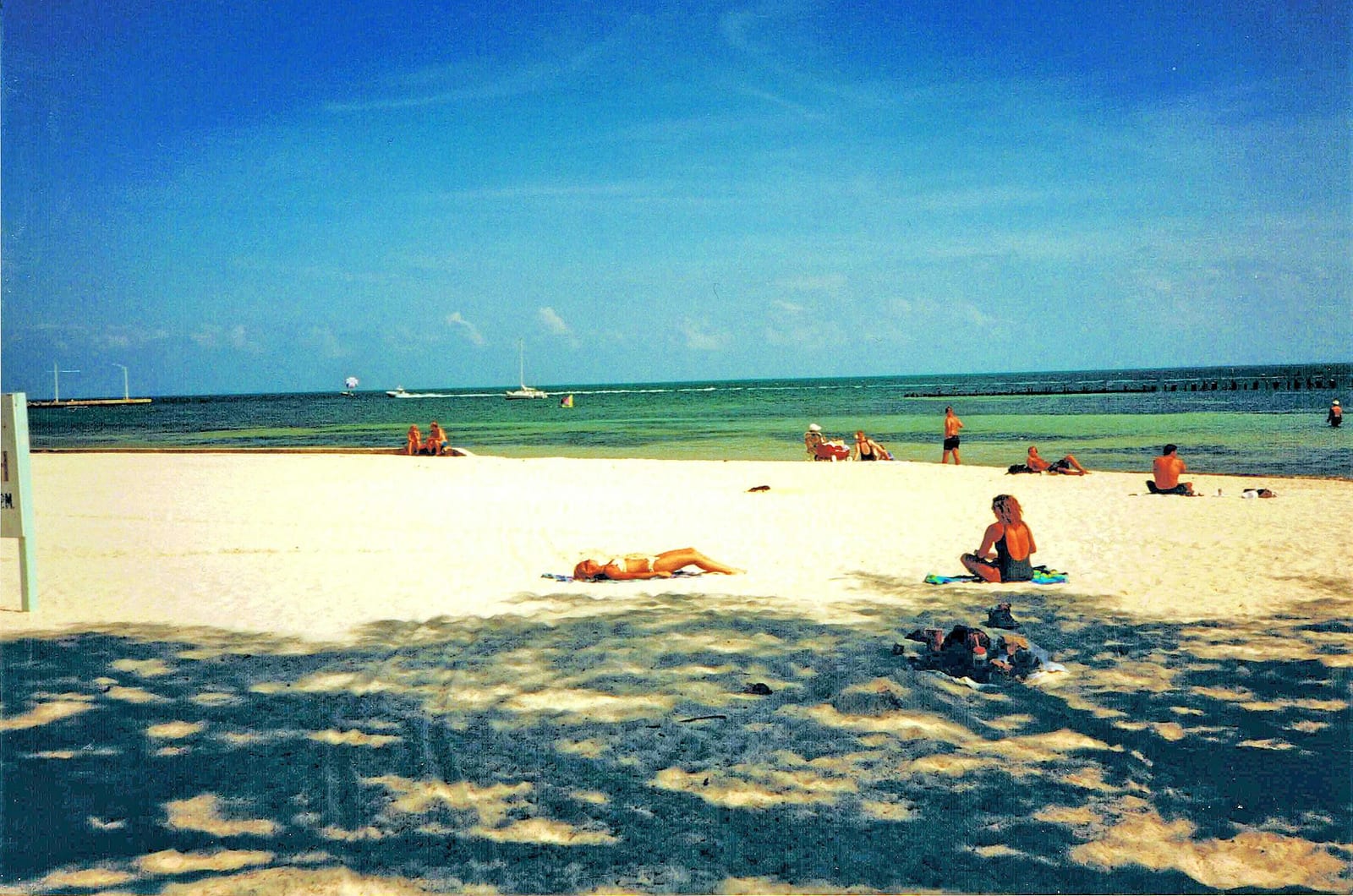Higgs Beach: sandy beach with swimmers, clear turquoise water, sailboats visible offshore
