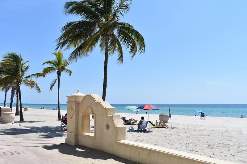 Hollywood Beach: palm trees, sandy beach, ocean, umbrellas, beachgoers, concrete structure