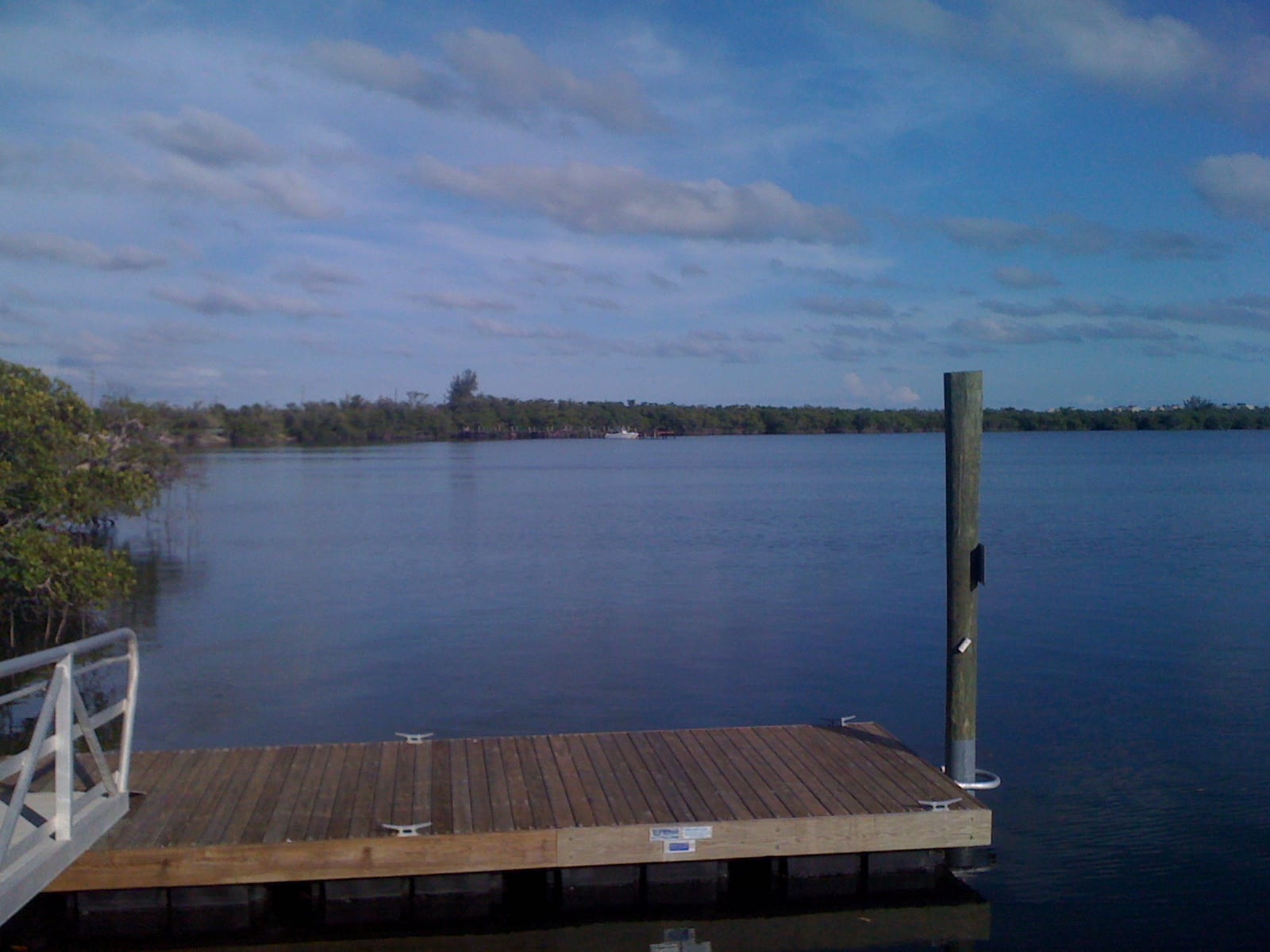 Jensen Beach: wooden dock and pier extending into calm blue water with trees