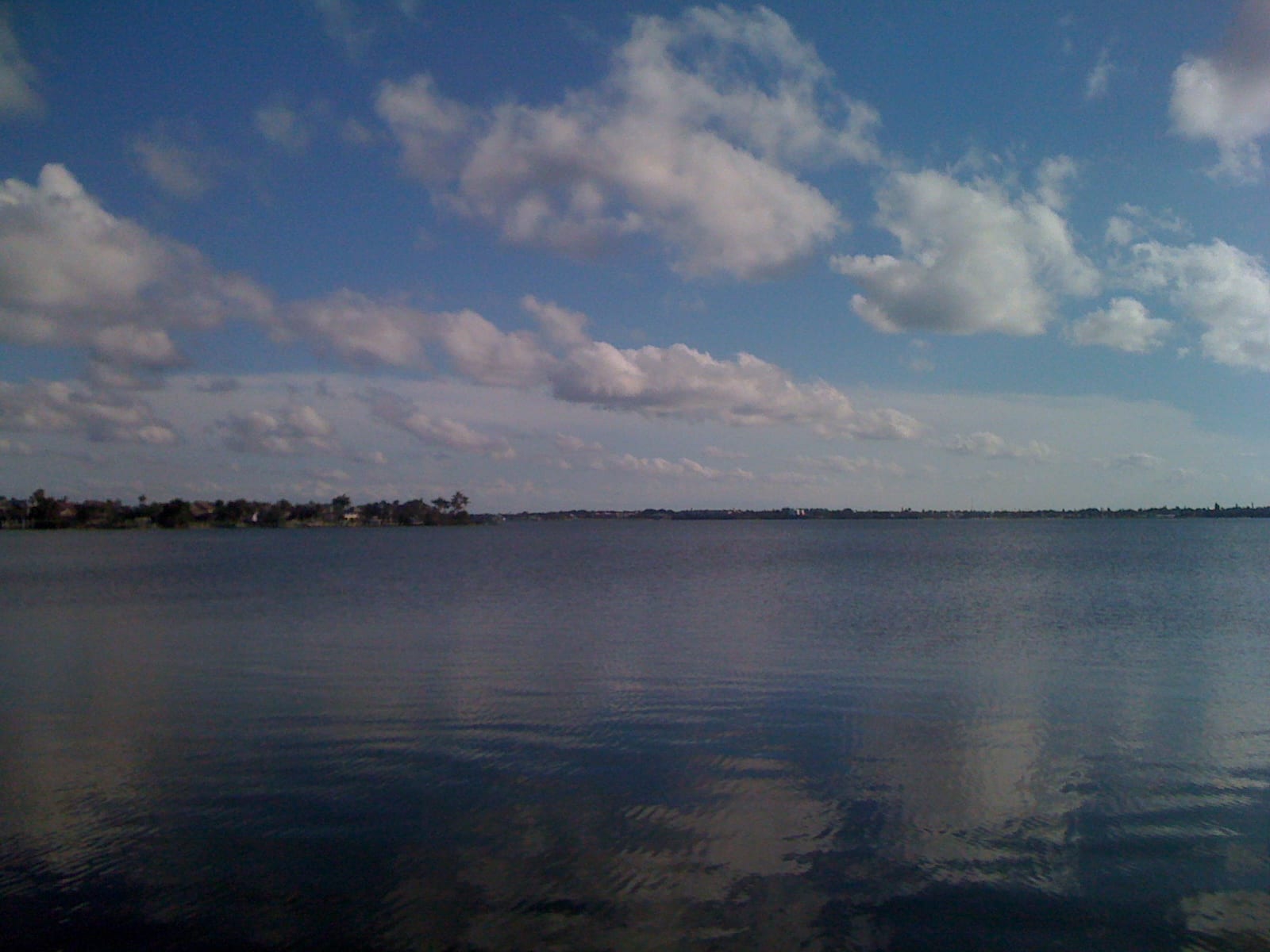 Jensen Beach: calm water with distant shoreline and clouds, no visible beach