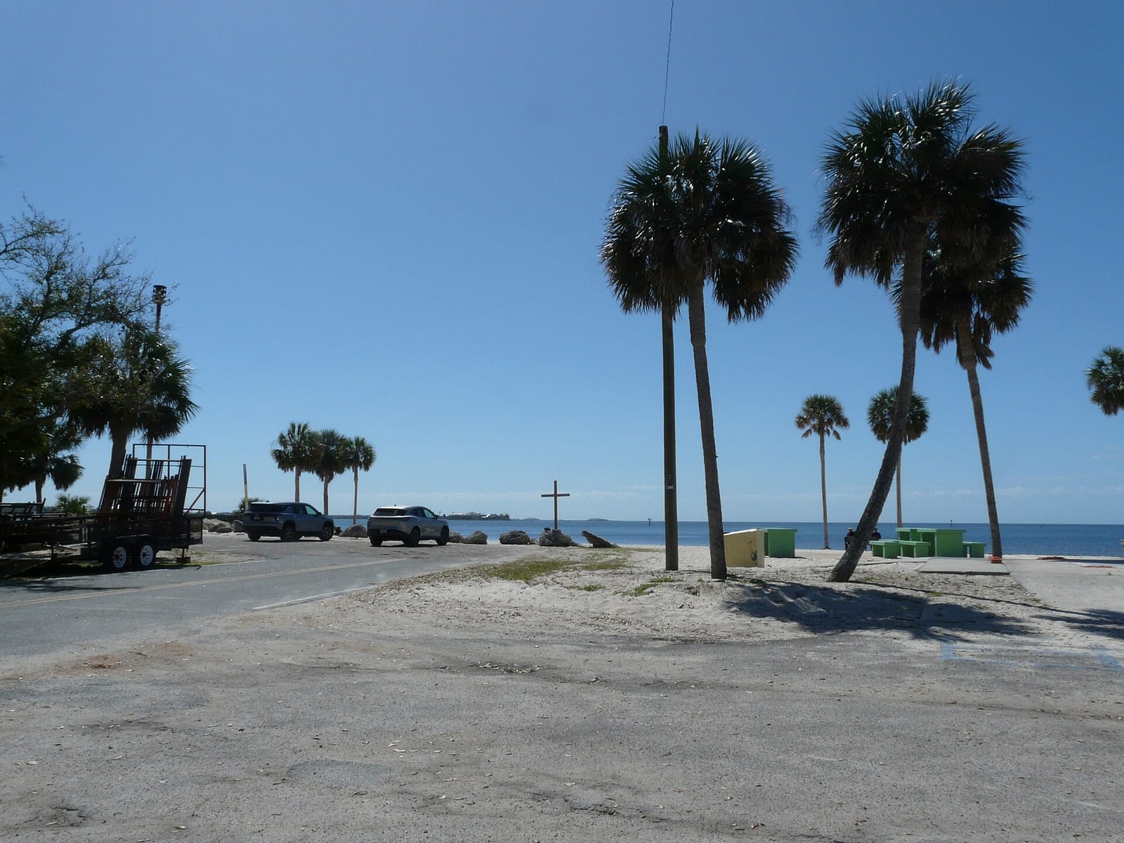 Keaton Beach: beachside parking area with palm trees, vehicles, and cross