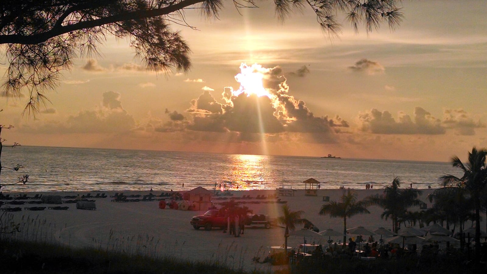 Lido Beach: sunset over ocean with beach, palm trees, and lifeguard station visible