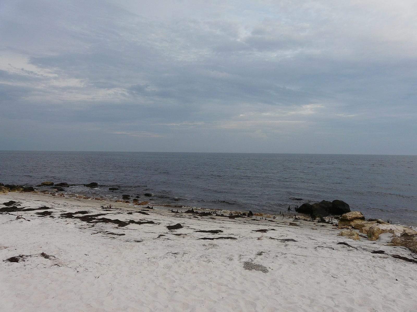Mashes Sands Beach: sandy beach with rocks, calm sea, and cloudy sky