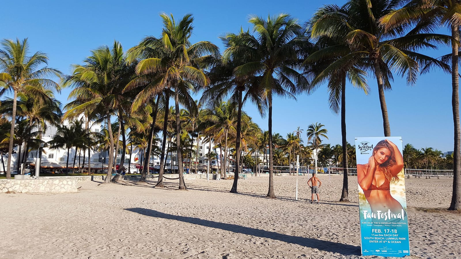 Miami Beach: sandy beach with palm trees, buildings, and festival banner