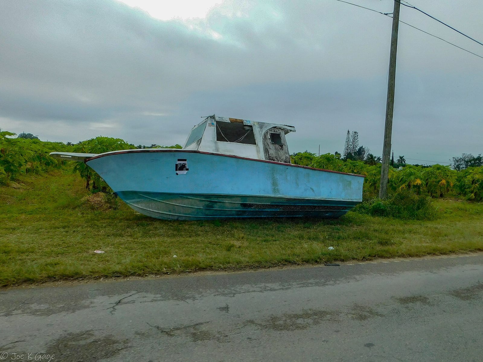North Beach: abandoned blue fishing boat on grassy ground near road