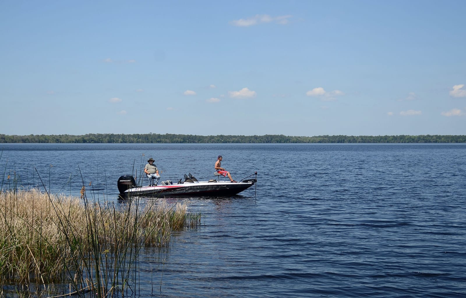Olustee Beach: fishing boat with two people on calm water near marsh grass