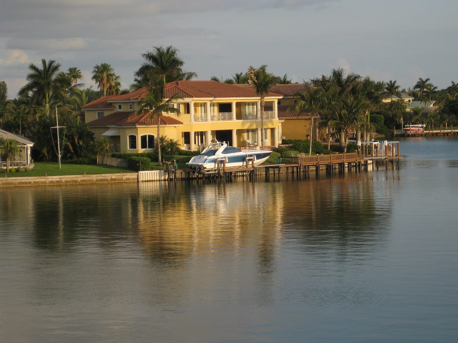 Park Shore Beach: waterfront mansion with palm trees, dock, and moored boat
