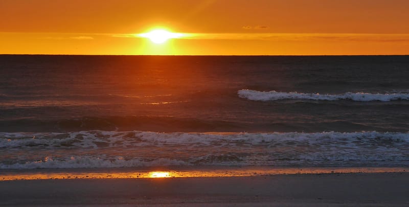 Pasa A Grille Beach: sunset over ocean with waves and sandy beach shore