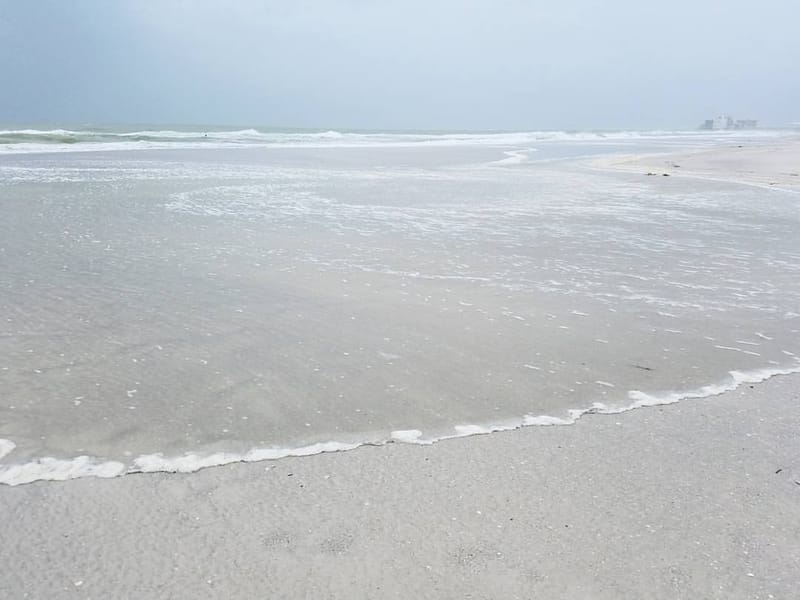 Pass-a-Grille Beach: sandy beach with gentle waves and overcast sky