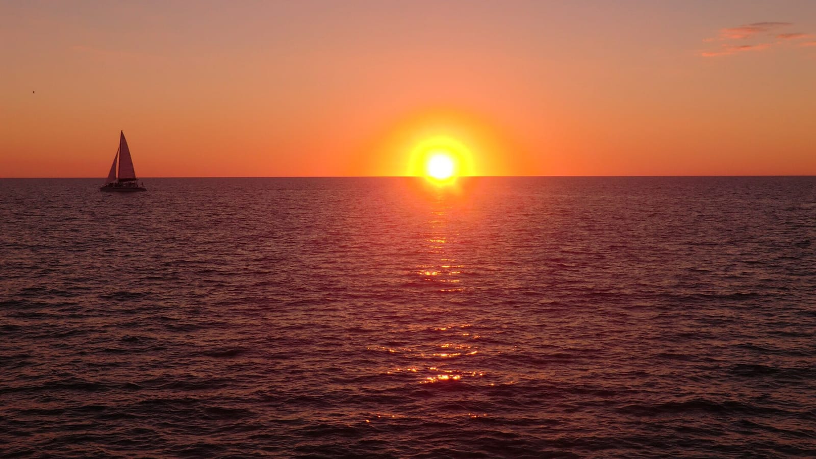 Public Access: sunset over ocean with sailboat on horizon