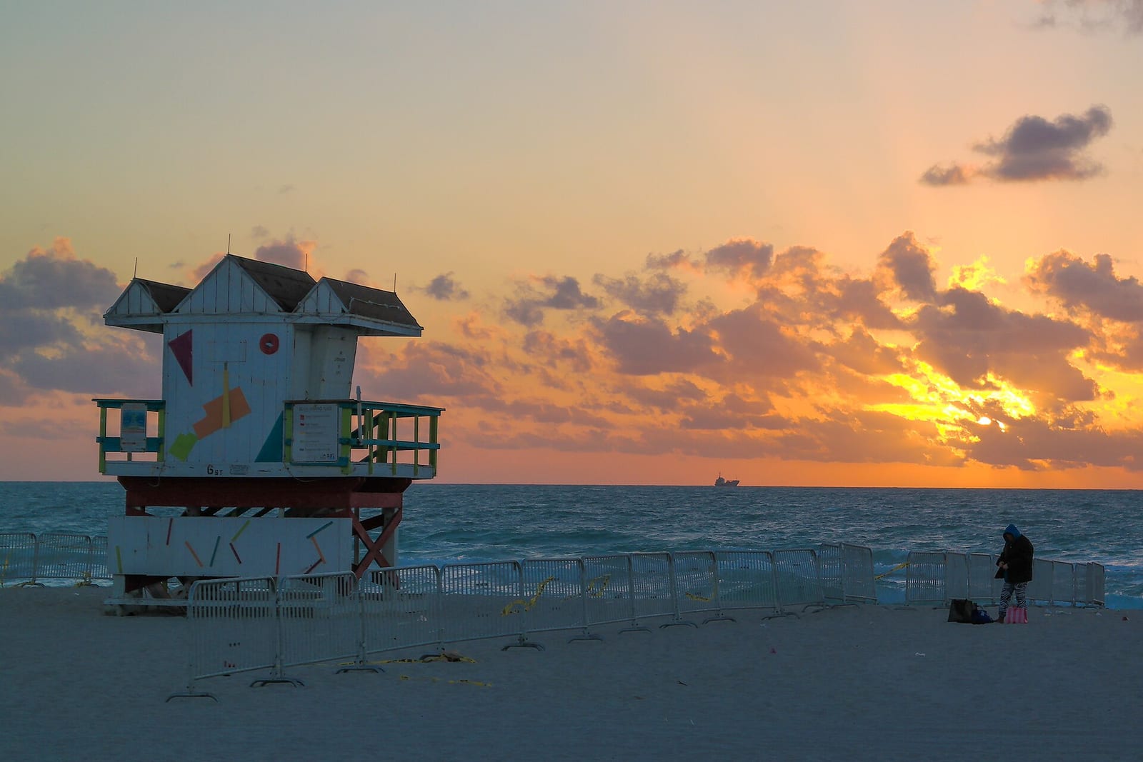 Sandy's Beach: lifeguard tower at sunset with ocean, beach, and distant figure