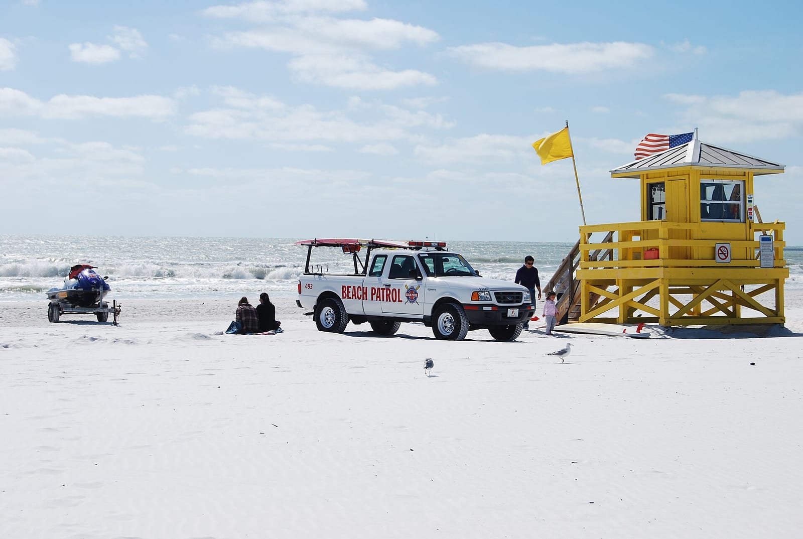 Siesta Beach: beach patrol vehicle and lifeguard station on sandy shore with ocean