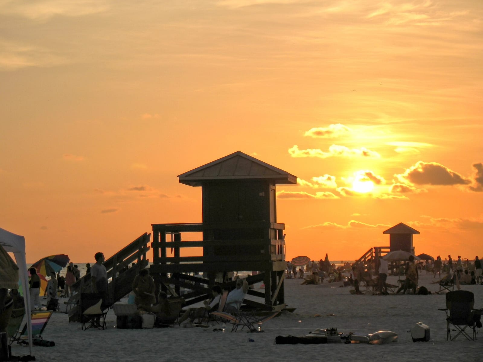 Siesta Beach: sunset over beach with lifeguard towers and scattered beachgoers