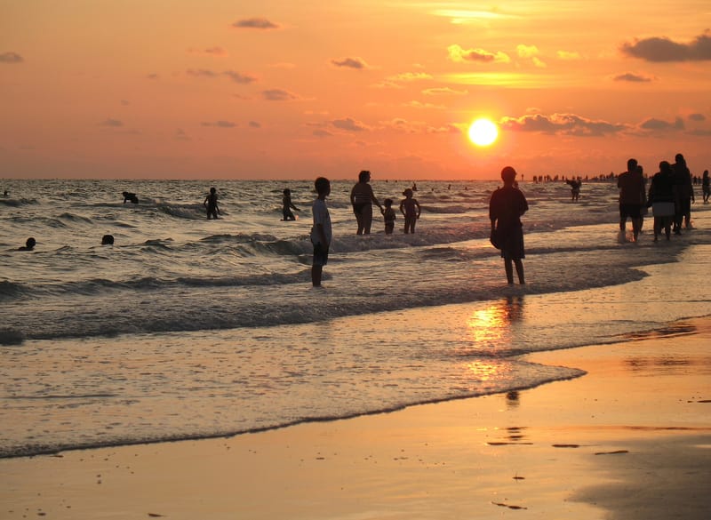 Siesta Beach: sunset over beach with swimmers and beachgoers in water and sand