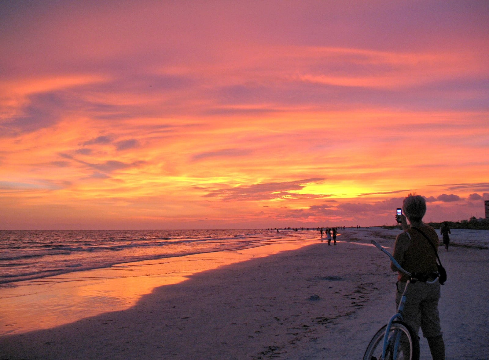 Siesta Key Beach: sunset over ocean with person on bicycle on beach