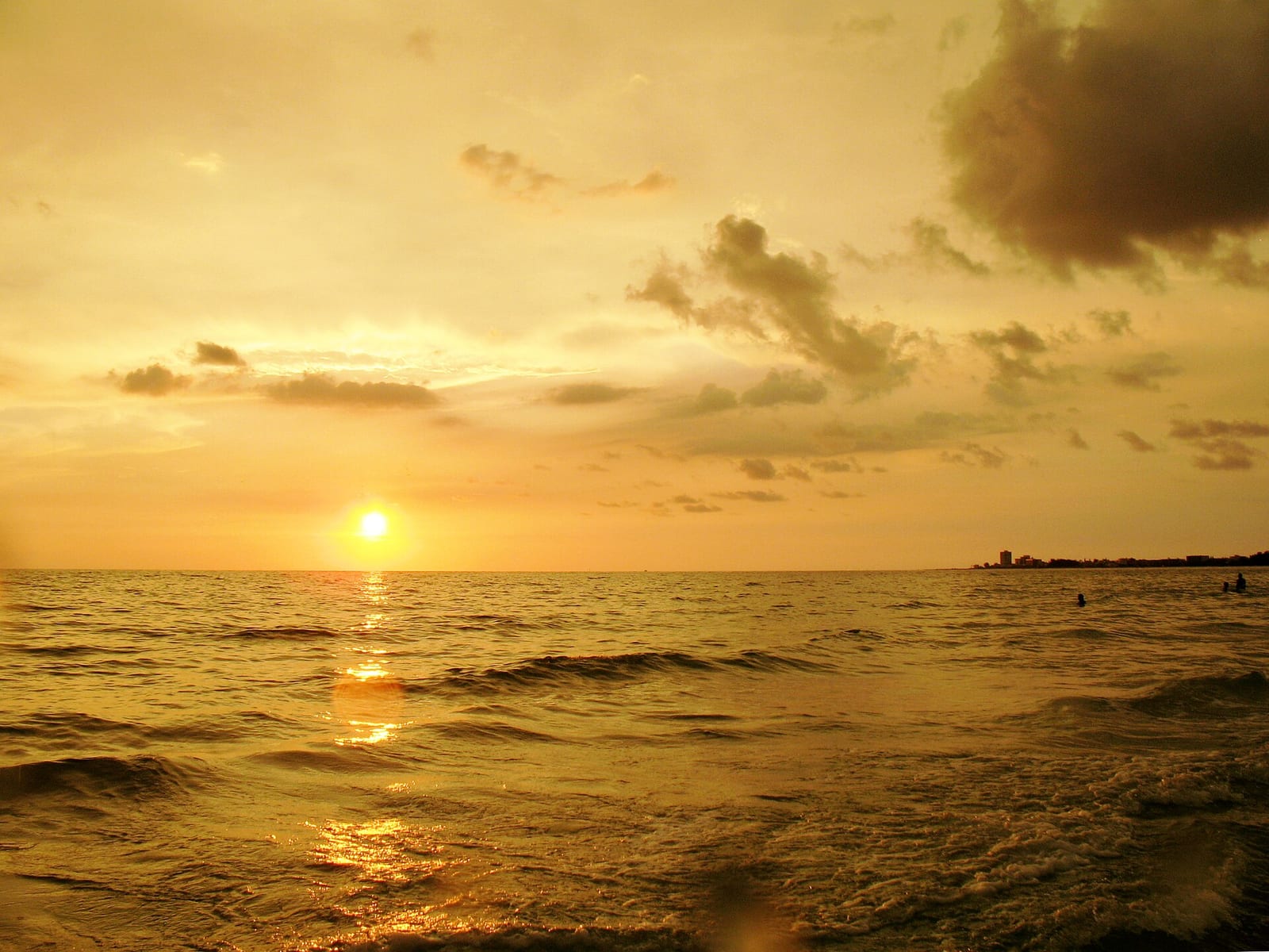 Siesta Key Beach: sunset over ocean with waves, clouds, and distant swimmers
