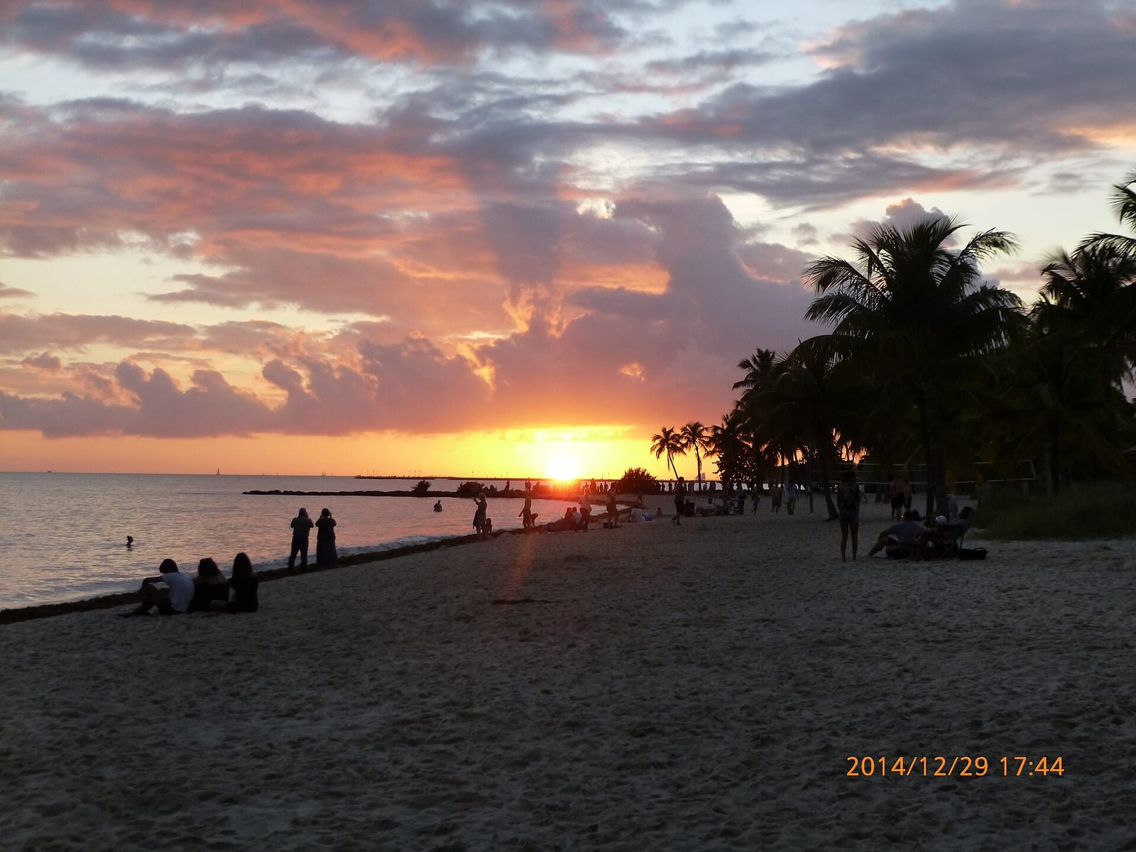Smathers Beach: sunset over ocean with beach, palm trees, and distant people