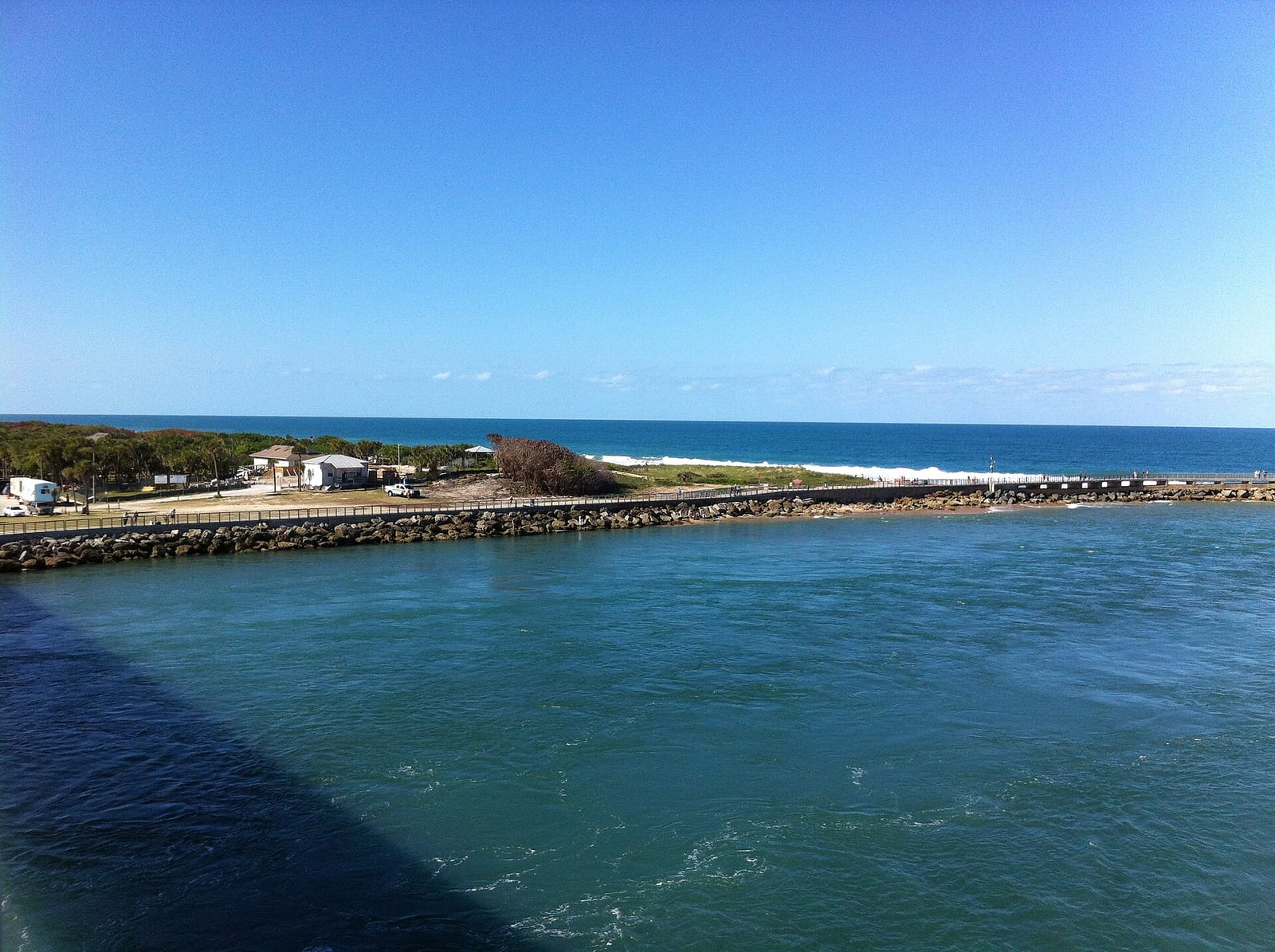 Tidal Cove Beach: harbor with pier, beach, and ocean under clear blue sky