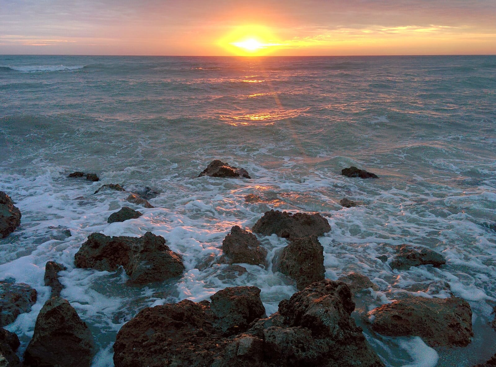 Venice Beach: sunset over ocean with rocky shoreline and waves
