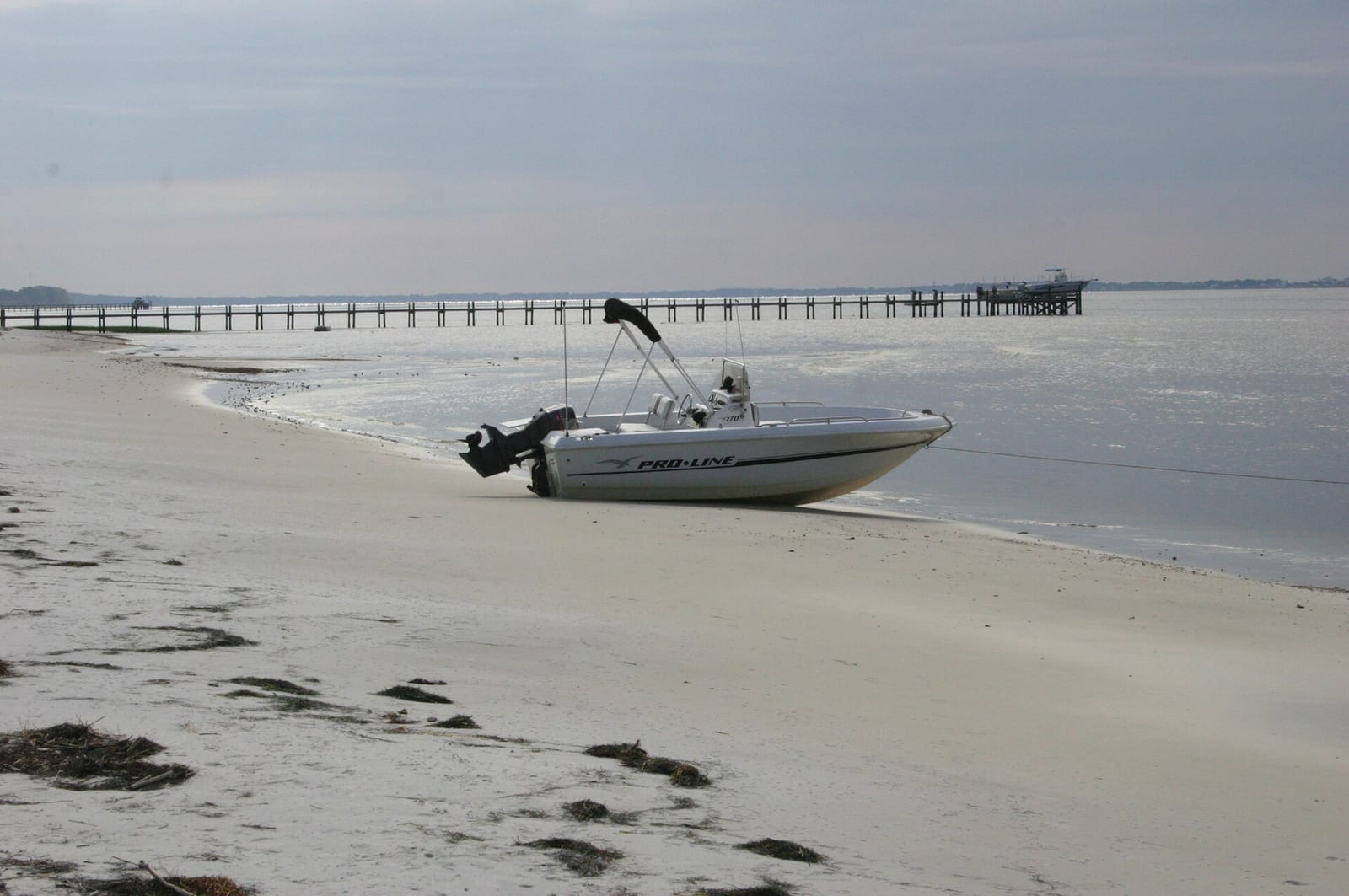 Wilson Beach: motorboat beached on sand with pier extending into calm water
